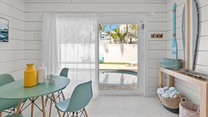 A room with a pool, a table with chairs, and a surfboard on the wall. - On Point: Across Street from Bean Point Beach, Outdoor Games & Pool by Anna Maria Life (Anna Maria)