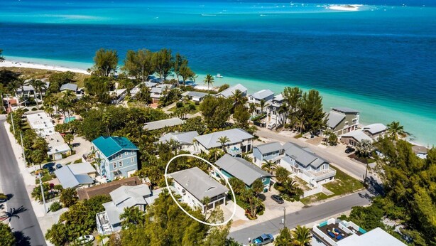 An aerial view of a coastal residential area with houses, a beach, and clear blue waters. - On Point: Across Street from Bean Point Beach, Outdoor Games & Pool by Anna Maria Life (Anna Maria)