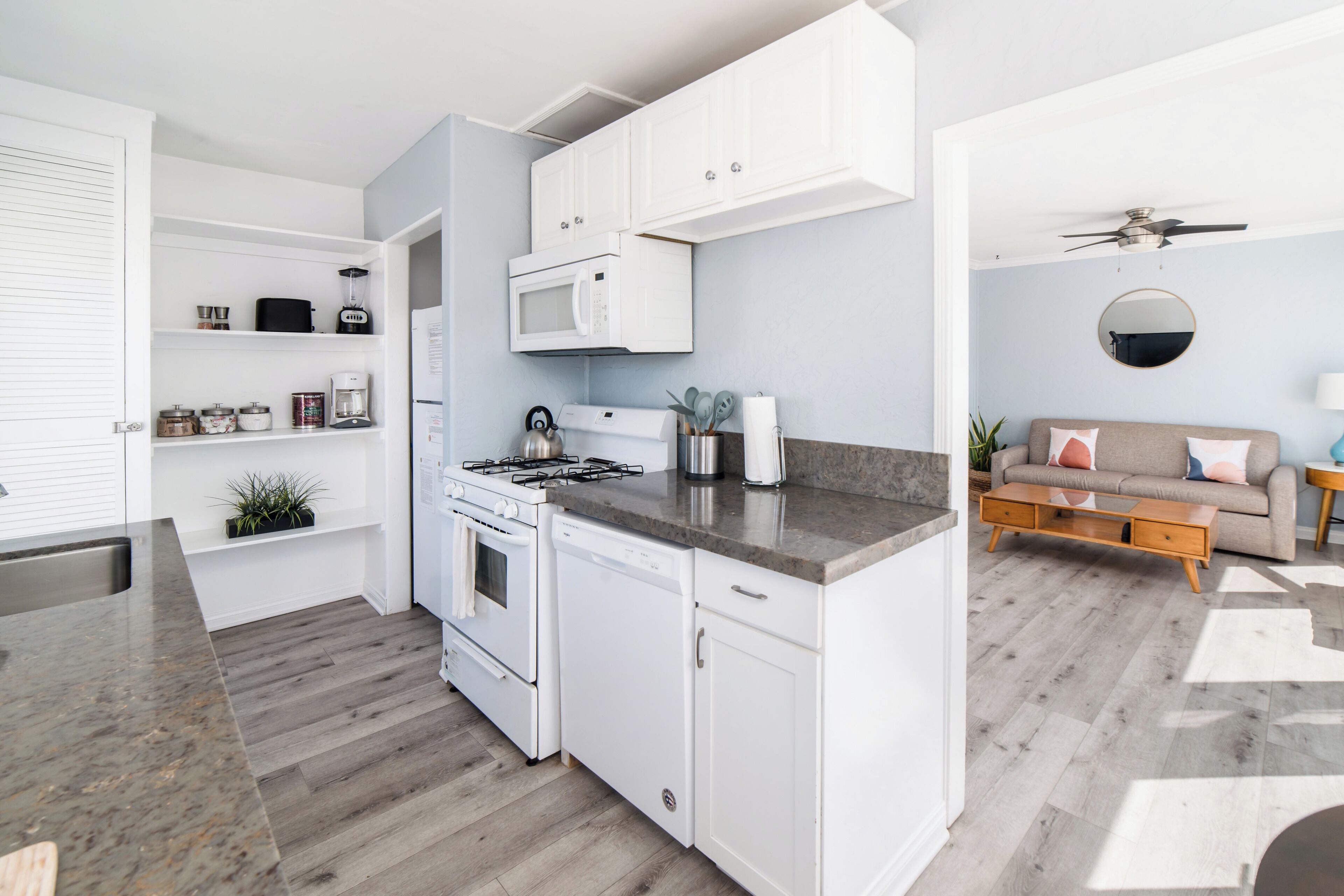 A modern kitchen with white cabinets, a built-in microwave, and a gas stove.