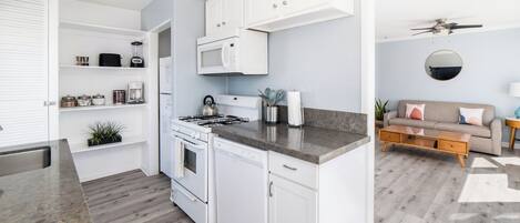 A modern kitchen with white cabinets, a built-in microwave, and a gas stove.