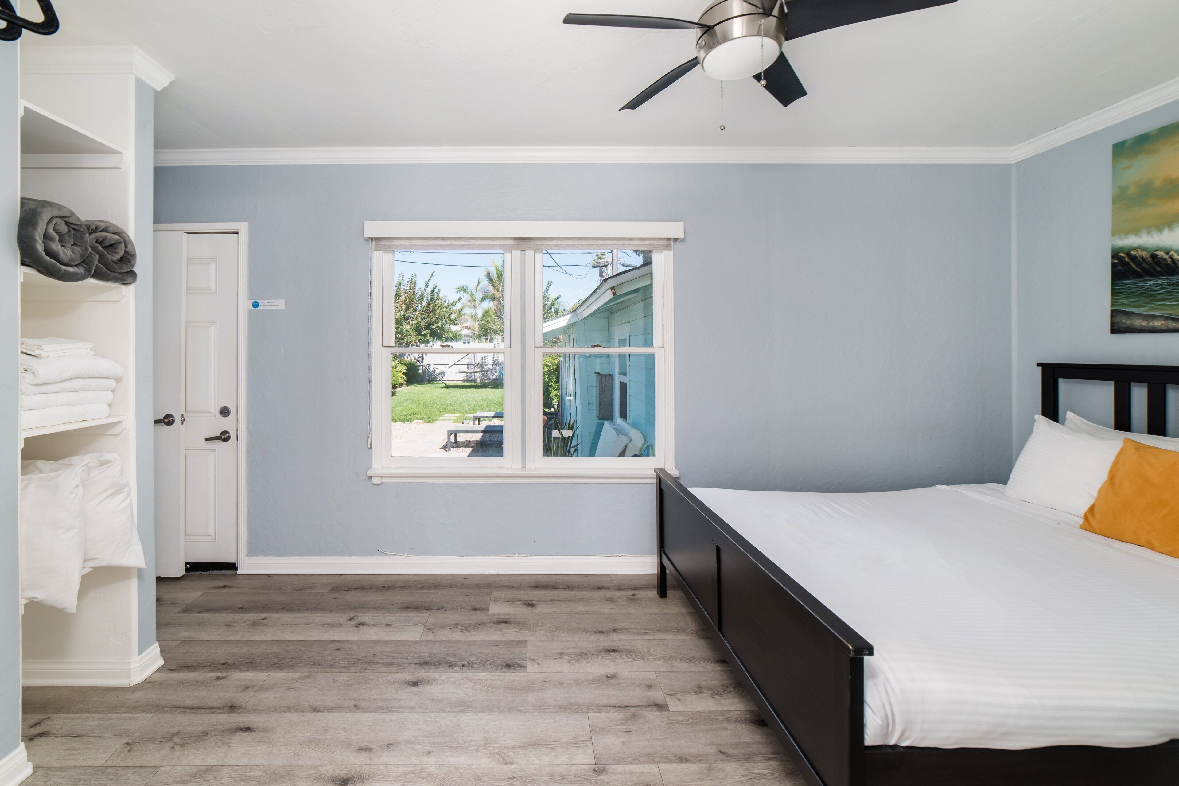 A bedroom with a bed, a ceiling fan, a window, and a door.
