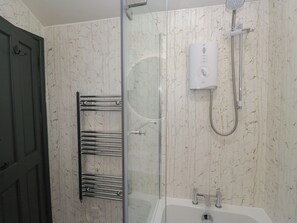 Un baño con ducha de vidrio, bañera blanca y un perchero para toallas.