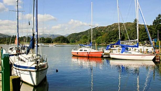 A marina with several sailboats docked, calm water, and a hilly landscape in the background. - Cringol Cottage (Ambleside)