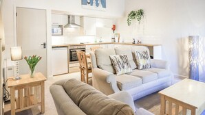 A modern living room with a sofa, a coffee table, and a dining area with a table and chairs. - Cringol Cottage (Ambleside)