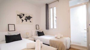 Habitación de hotel con dos camas, un mapa mundial en la pared y una puerta corrediza de vidrio al exterior.