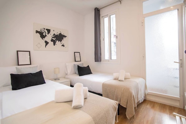 A hotel room with two beds, a world map on the wall, and a sliding glass door to the outside.