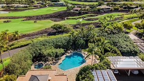 Ett semesterhotell med en swimmingpool omgiven av frodig grönska, en golfbana och solpaneler.
