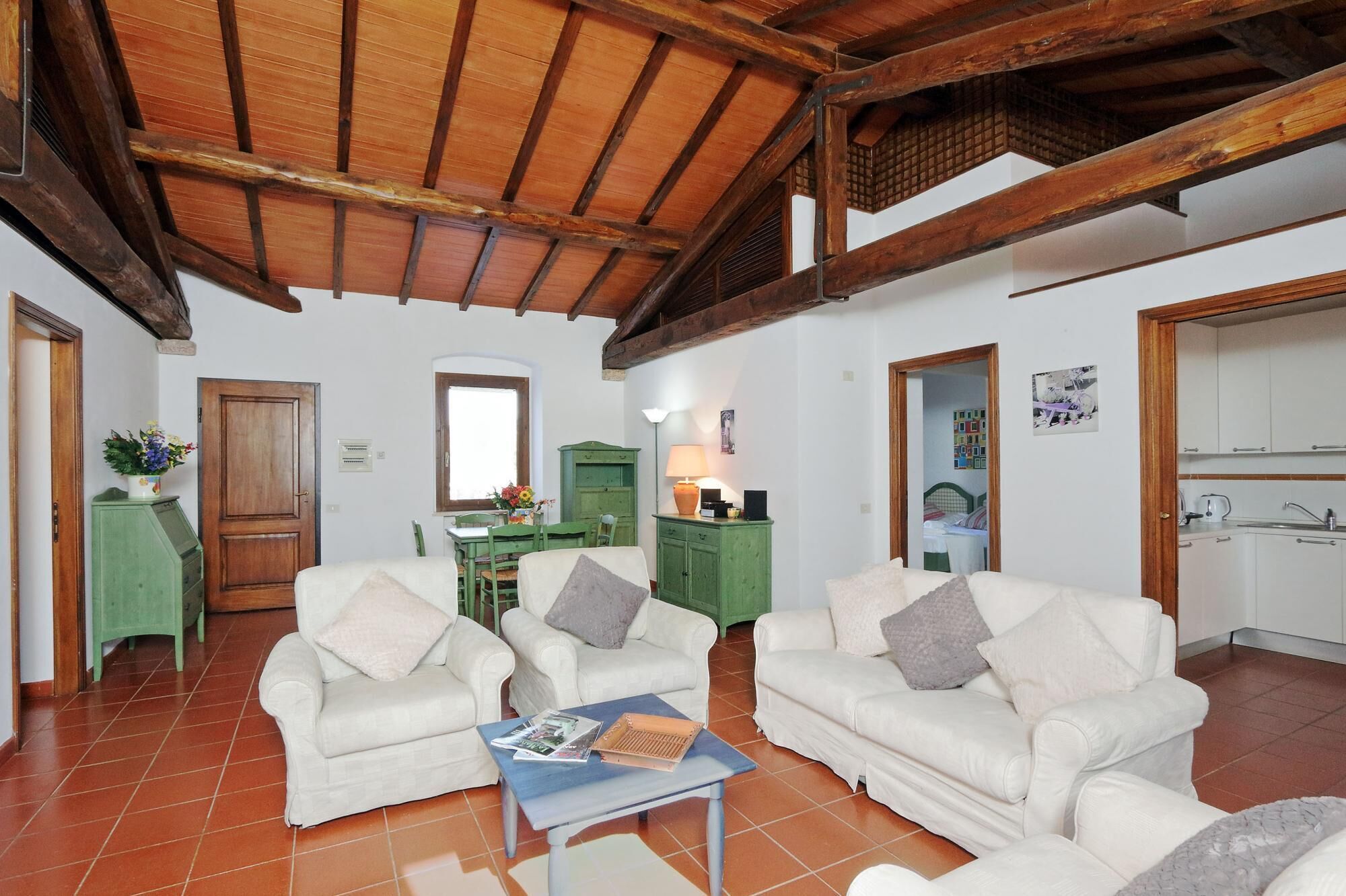 A spacious living area with two white sofas, a coffee table, and a green cabinet.