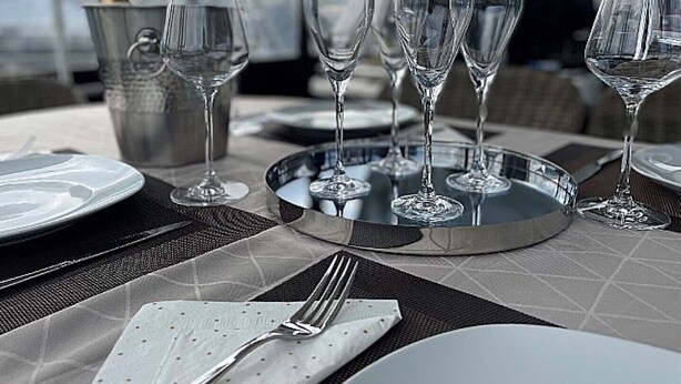 Una mesa dispuesta para una comida, con copas de vino, una botella de champán y una bandeja de plata.