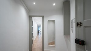 A hallway with a wooden floor, a door with a security device, and a mirror on the wall. - Sagrada Familia bright apartment with balcony (08013 Barcelona)