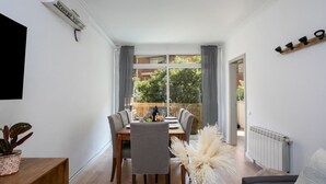A dining area with a table and chairs, a potted plant, and a radiator. - Sagrada Familia bright apartment with balcony (08013 Barcelona)