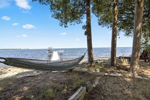 A hammock tied between trees, a dock extending into the water, and a bench under a tree. - Private 100' Waterfront, 4BR - Heidaway Cottage (Sturgeon Bay)