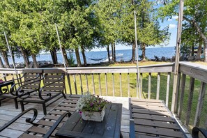A wooden deck with benches and a table, overlooking a body of water with boats and trees. - Private 100' Waterfront, 4BR - Heidaway Cottage (Sturgeon Bay)