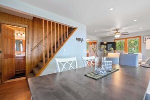 A modern kitchen with wooden cabinets, a dining area with a dark wooden table, and a staircase with wooden railings. - Private 100' Waterfront, 4BR - Heidaway Cottage (Sturgeon Bay)