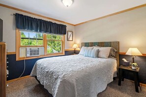 A bedroom with a large bed, two bedside lamps, a window with curtains, and a radiator. - Private 100' Waterfront, 4BR - Heidaway Cottage (Sturgeon Bay)