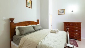 Ein Schlafzimmer mit einem hölzernen Bett, einer Kommode und zwei gerahmten Bildern an der Wand.