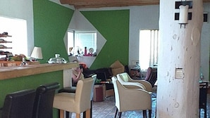 A rustic interior with a wooden ceiling, a green wall, and a bar area with chairs. - Dominating Olywood One (Sarajevo)