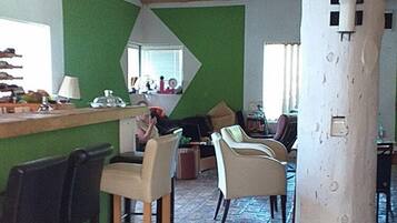 Un intérieur rustique avec un plafond en bois, un mur vert et un coin bar avec des chaises.