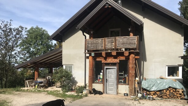 A rustic lodge with a wooden porch, a door labeled "OAKWOOD," and a gravel driveway. - Dominating Olywood One (Sarajevo)
