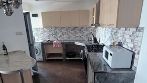 A compact kitchen with a washing machine, a microwave, and a stove.
