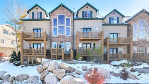 A multi-story building with a stone facade, wooden balconies, and a central entrance.