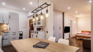 Een moderne keuken met witte kasten, een houten eettafel en een boek op tafel.