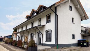Een woonhuis met twee verdiepingen, een witte gevel, zwarte accenten en een pannendak.