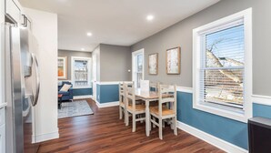 A modern kitchen with a built-in refrigerator, wooden dining table, and chairs.