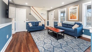 A living room with two blue sofas, a wooden coffee table, and patterned rugs.