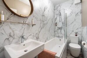 A bathroom with two sinks, a bathtub, a toilet, and a shower.