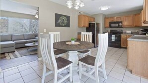 A modern kitchen with wooden cabinets, a central island, and a dining area with white chairs. - Quiet Getaway, Travis' Place! Affordable Location (Rossville)