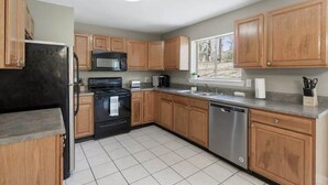 A modern kitchen with wooden cabinets, a black refrigerator, a microwave, a stove, and a dishwasher. - Quiet Getaway, Travis' Place! Affordable Location (Rossville)