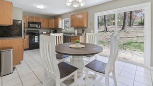 A kitchen with wooden cabinets, a stainless steel refrigerator, a microwave, and a dining area with a round table and white chairs. - Quiet Getaway, Travis' Place! Affordable Location (Rossville)