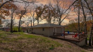 A single-story house with a fenced deck, surrounded by trees and a grassy yard. - Quiet Getaway, Travis' Place! Affordable Location (Rossville)