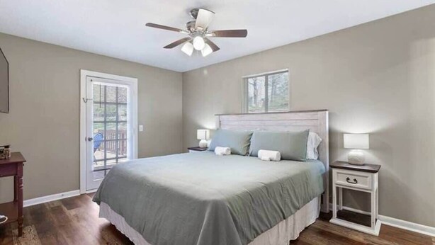A bedroom with a bed, bedside tables, a ceiling fan, and a door leading to a balcony. - Quiet Getaway, Travis' Place! Affordable Location (Rossville)