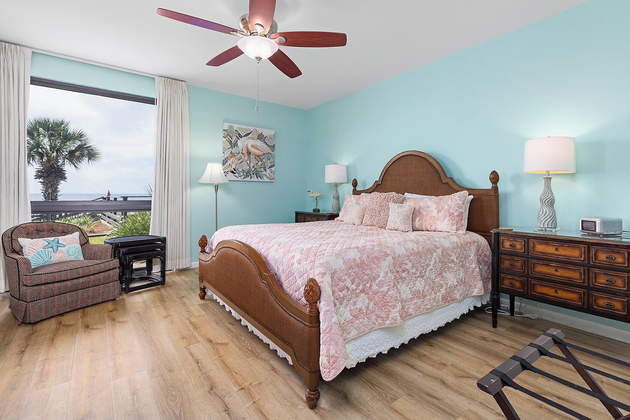 Une chambre à coucher comprenant un lit, une chaise, une table de chevet, une commode et un ventilateur de plafond.
