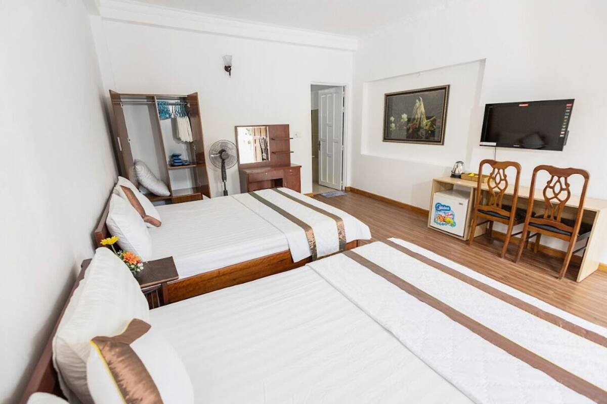 A hotel room with a bed, a desk, a chair, a wardrobe, a mirror, a television, and a picture on the wall.