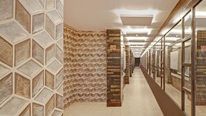 A hallway with geometric patterned walls, a central column, and a glass door on the right.