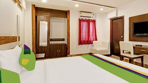 A hotel room with a bed, a desk, a chair, a TV, and a wardrobe.