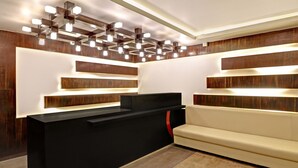 A reception area with a black counter, wooden panel walls, and a beige sofa.