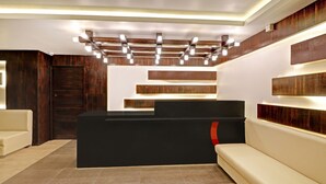 A reception area with a black reception desk, beige sofas, and a wooden accent wall.