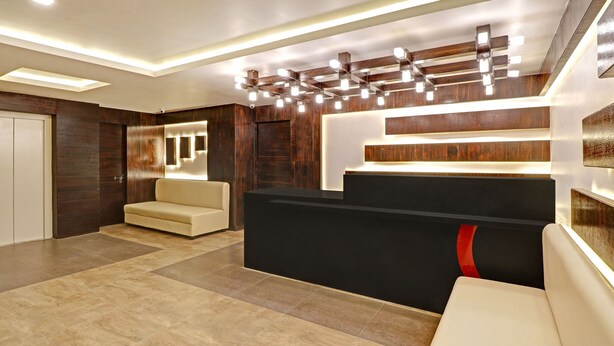 A reception area with a black reception desk, beige sofas, and a wooden wall with recessed lighting.