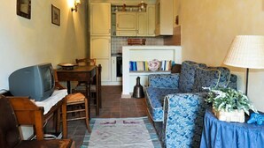 A cozy living room with a television, sofa, and dining area. - MACETONA - MACETONA-SUITE (San Casciano dei Bagni)