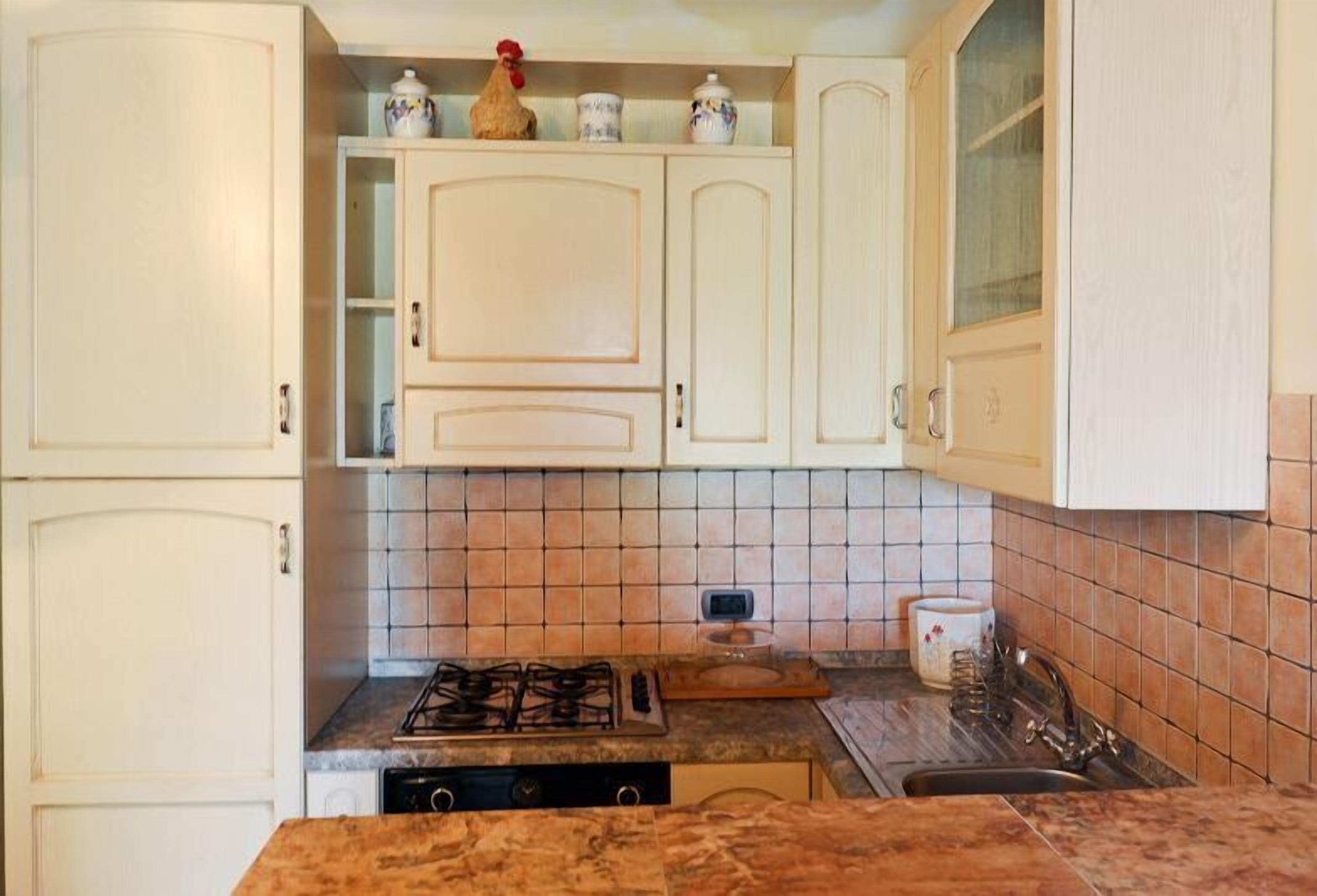 A kitchen with white cabinets, a gas stove, a microwave, and a tiled backsplash.