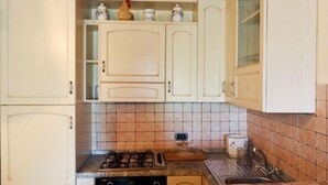 A kitchen with white cabinets, a gas stove, a microwave, and a tiled backsplash. - MACETONA - MACETONA-SUITE (San Casciano dei Bagni)