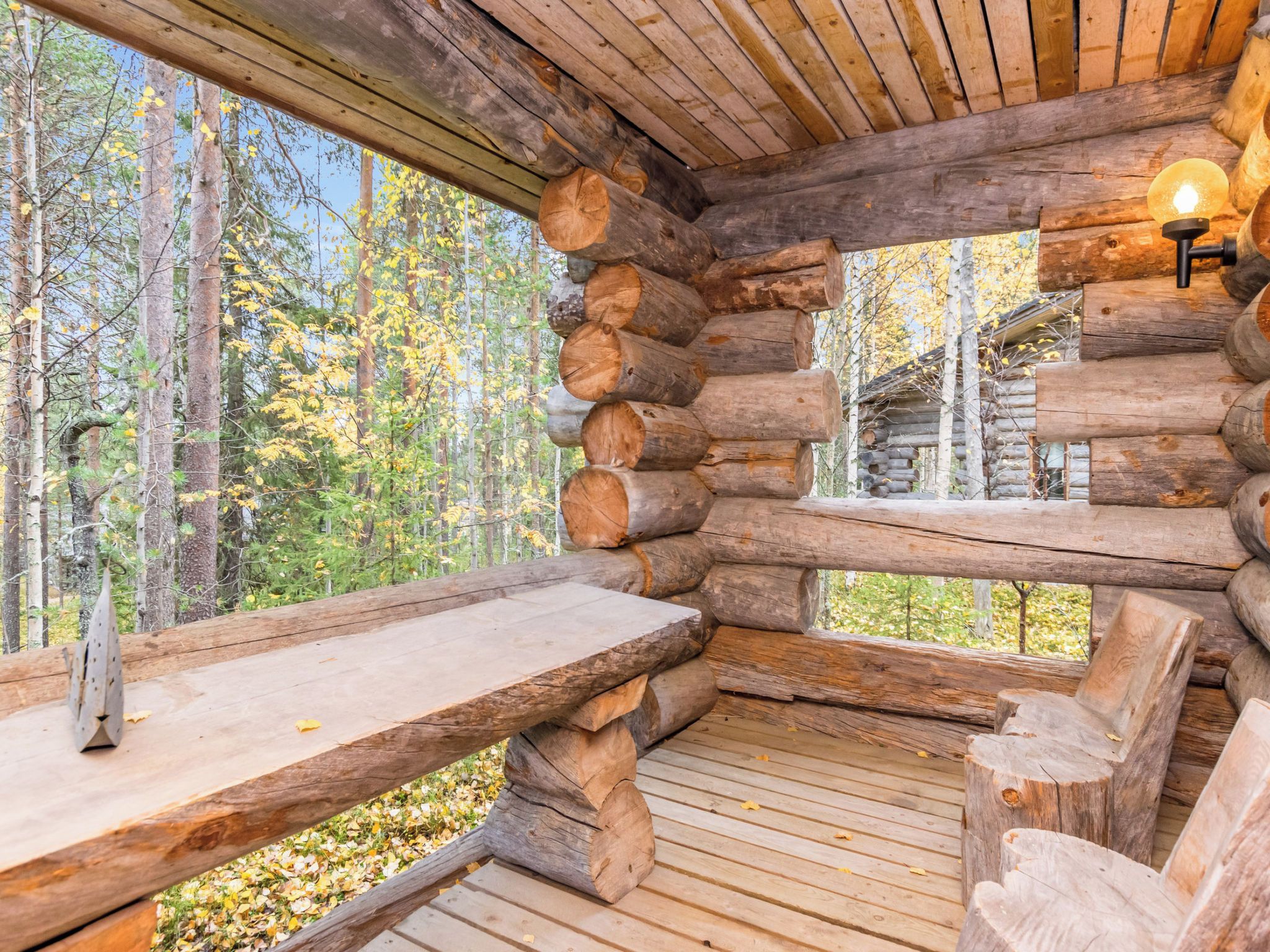 A log cabin interior with a wooden deck, a bench, and a table.