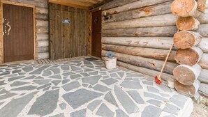Una cabaña de troncos con piso de losas de piedra, paredes de madera y una puerta con un cartel.