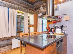 A kitchen with a central island, wooden chairs, a stove, and a coffee maker.