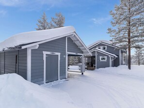 Un quartier résidentiel avec deux maisons recouvertes de neige, un ciel dégagé et un arbre en arrière-plan.