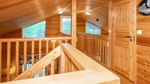 Un intérieur en bois avec un escalier, des murs en bois et une porte au motif noir et blanc.